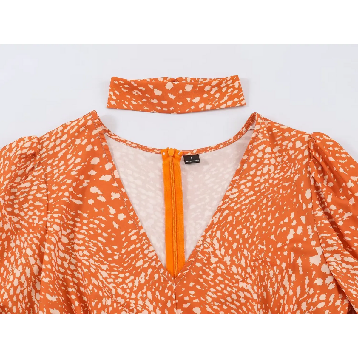 Close-up of v-neck and front zipper on abstract print maxi dress, paired with separate matching fabric choker