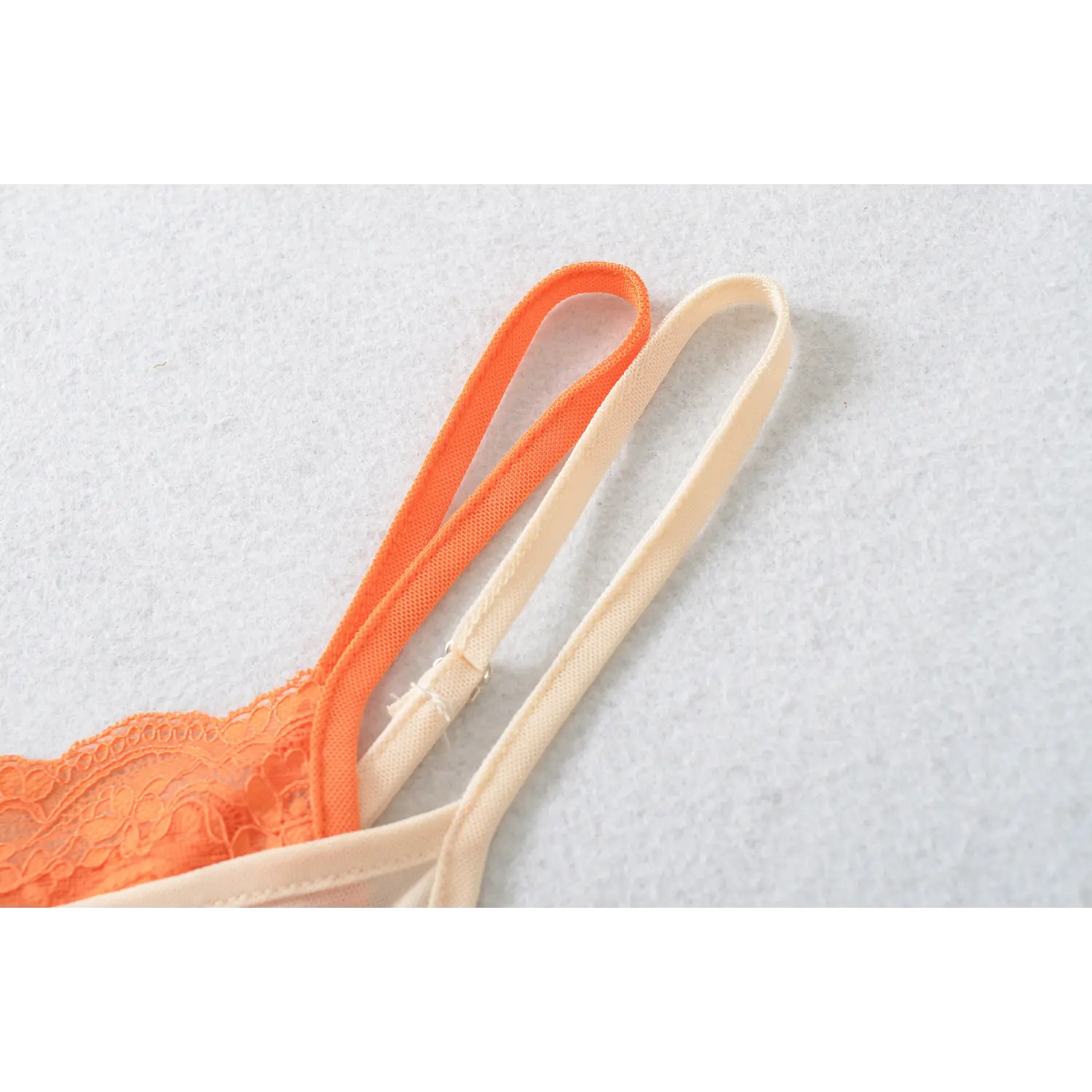 Adjustable dual thin straps cami macro flat close-up, orange apricot color woven straps metal slider buckle matching lace lined mesh cami white background shot