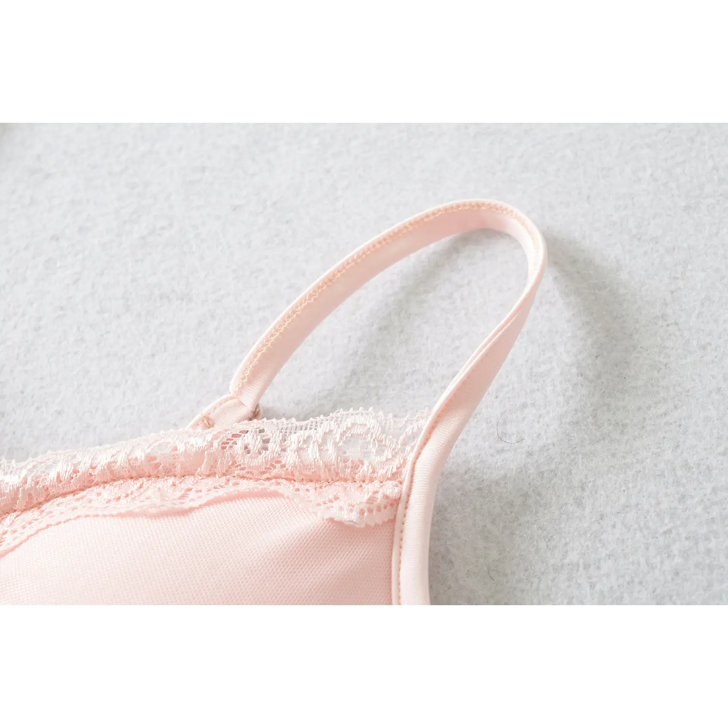 Shoulder strap partial shot, slider adjuster buckle, finished piping edge, hollow floral lace trim along V neck