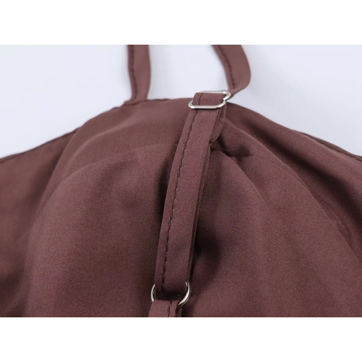 Macro close-up of metal adjuster slider on brown spaghetti strap for polka dot maxi dress, fine neat stitching