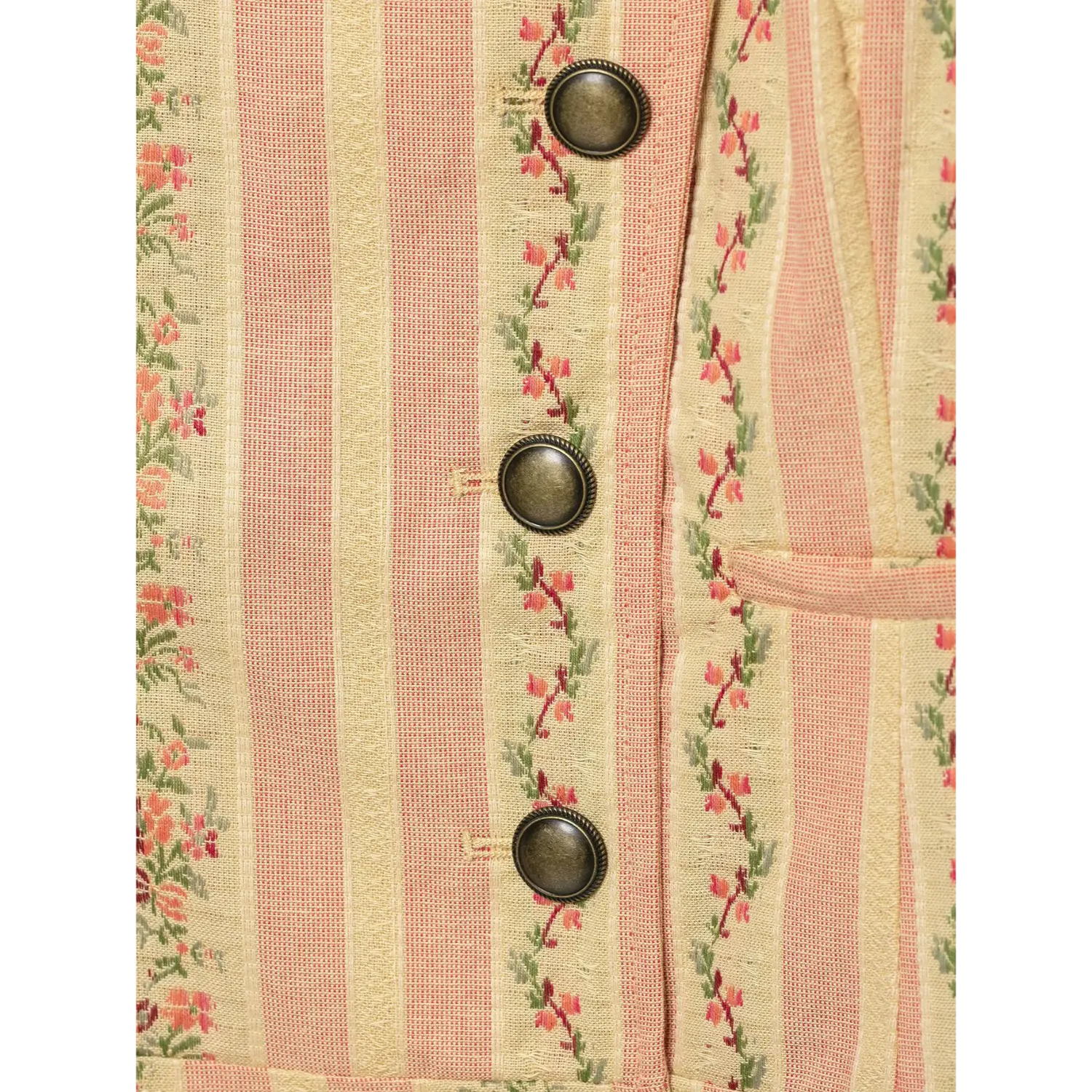 Macro close-up vintage bronze buttons paired with pink vine floral stripe textured woven fabric of cropped jacket