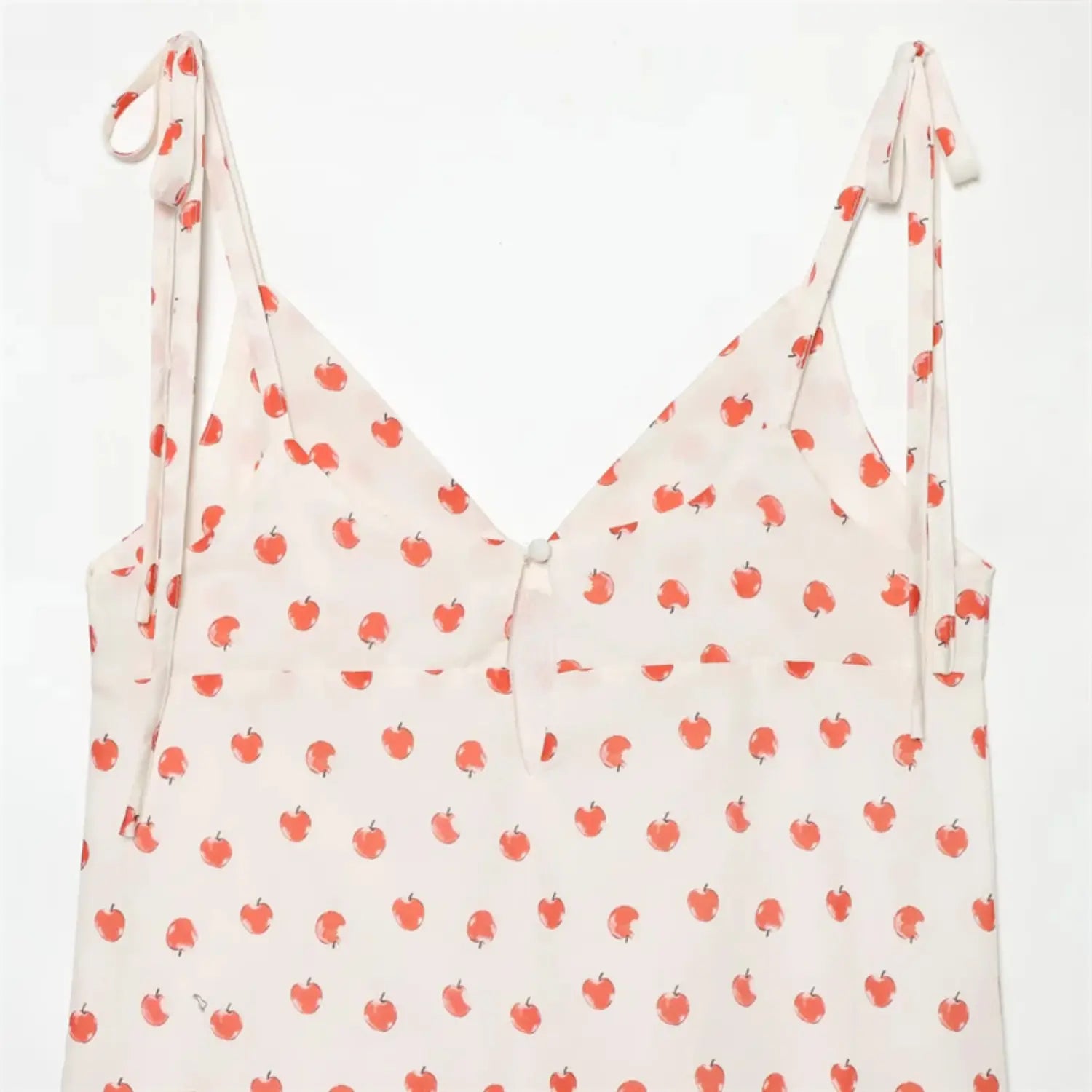 Macro shot back neck teardrop keyhole cutout, matching fabric round button closure, full apple print fabric, clean folded binding stitching