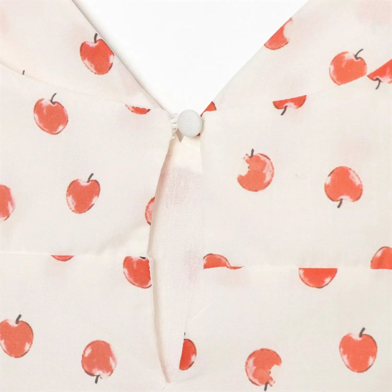 Extreme closeup rear neck hollow keyhole edge, neat folded binding stitching, consistent red apple fruit print pattern