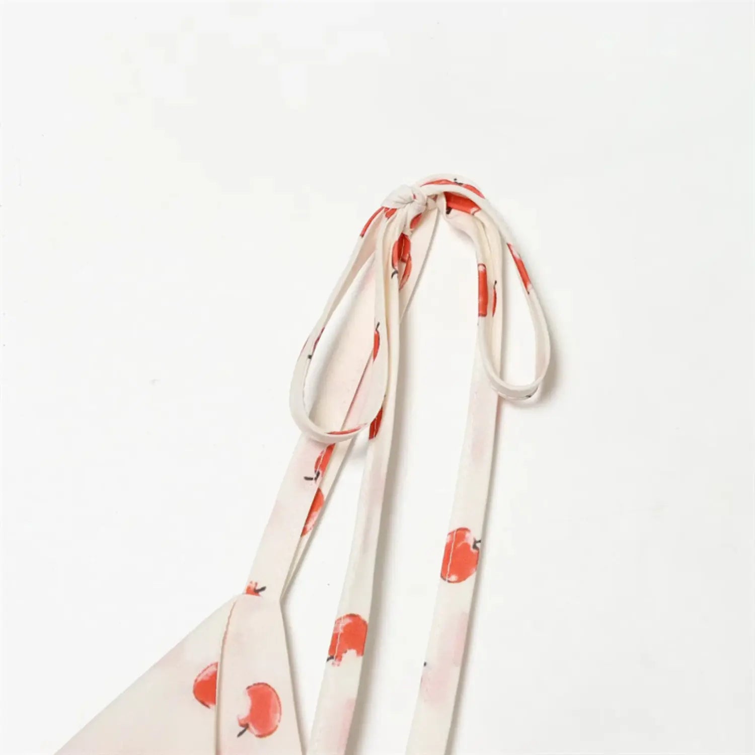 Shoulder self-fabric tie strap detail, adjustable hand-tied ribbon loop, apple print matching strap fabric, smooth woven texture