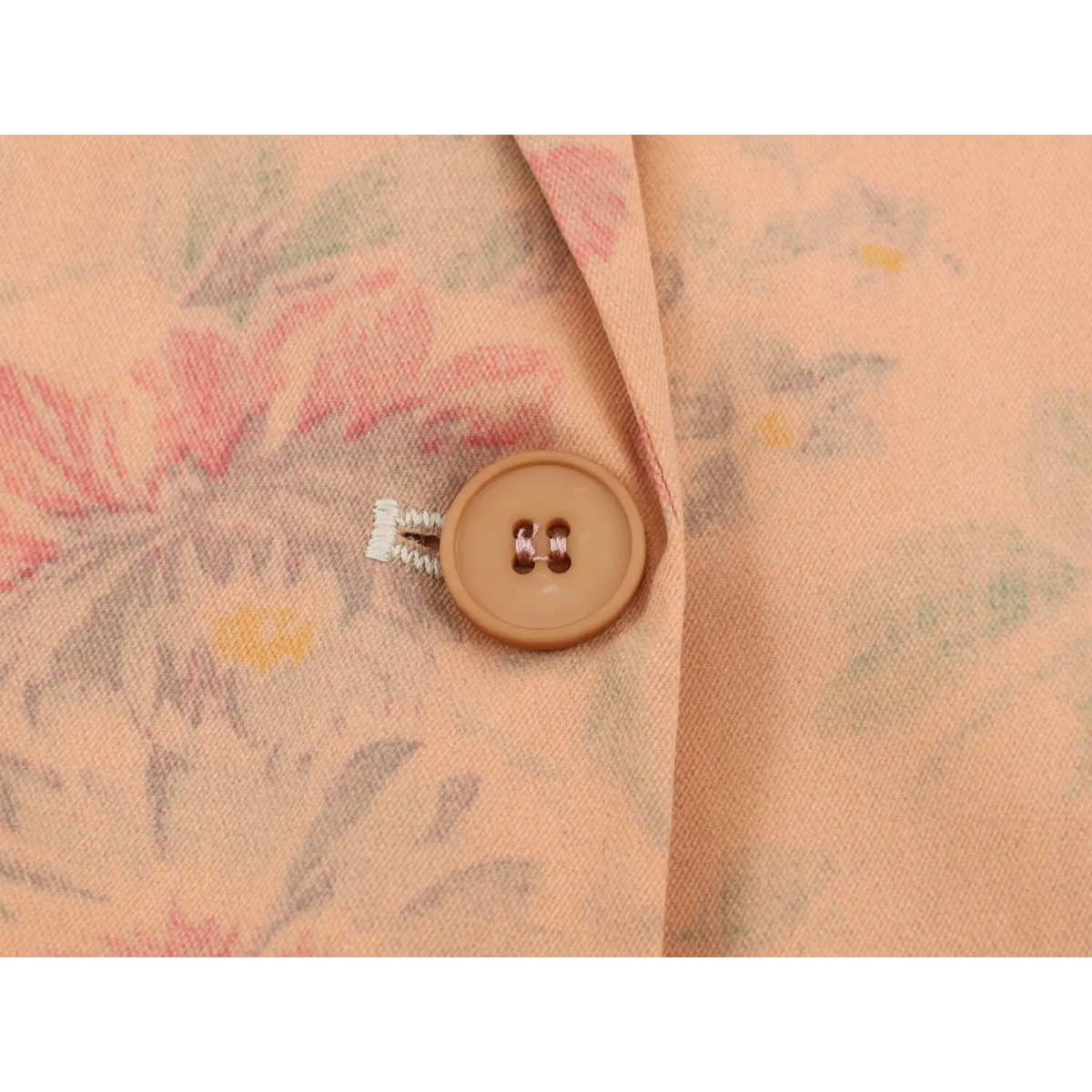 Close-up of single tan button on front placket