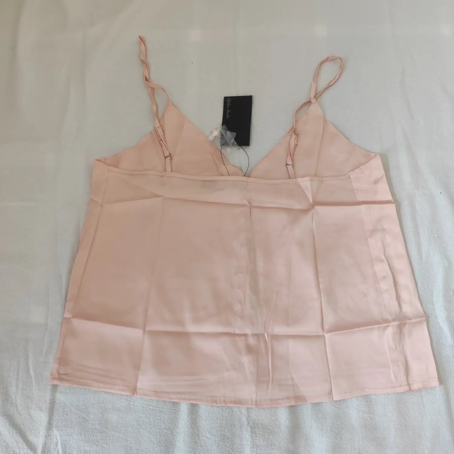 Flat lay back view apricot pink satin cami top with adjustable spaghetti straps and inner stitching