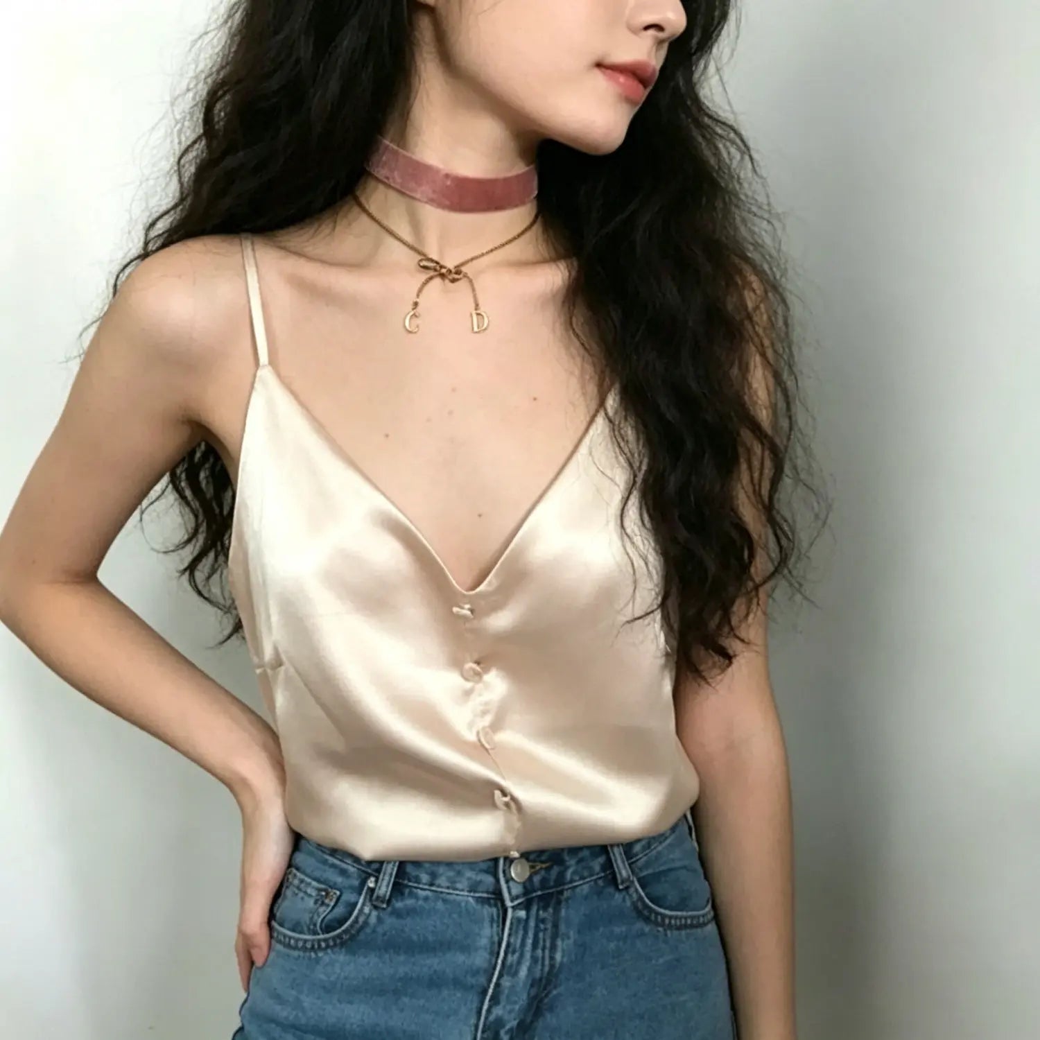 Model front waist shot apricot pink satin cami top v‑neck front button detail paired with blue jeans