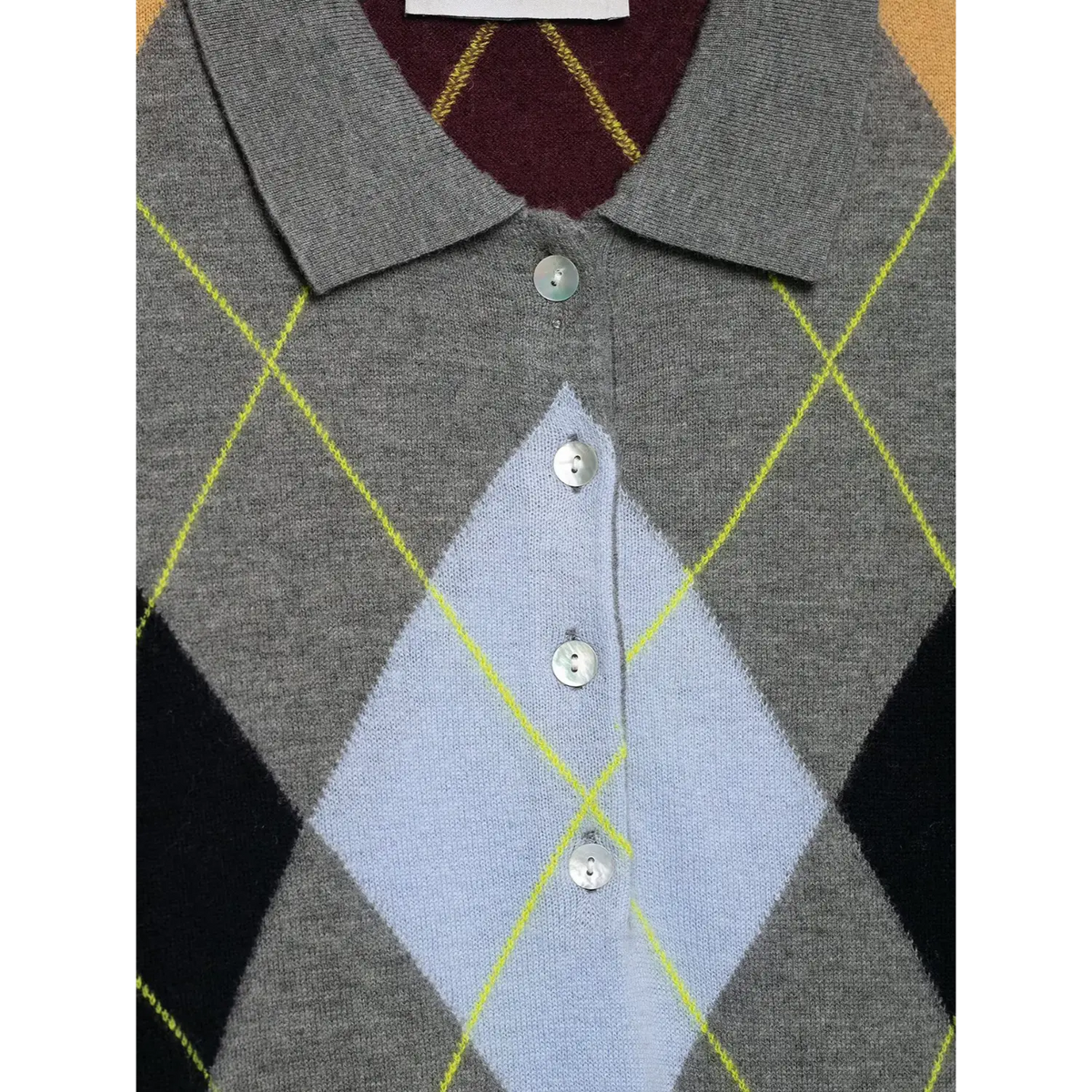 Close-up of pearl tone buttons and argyle diamonds at neckline of knit sweater