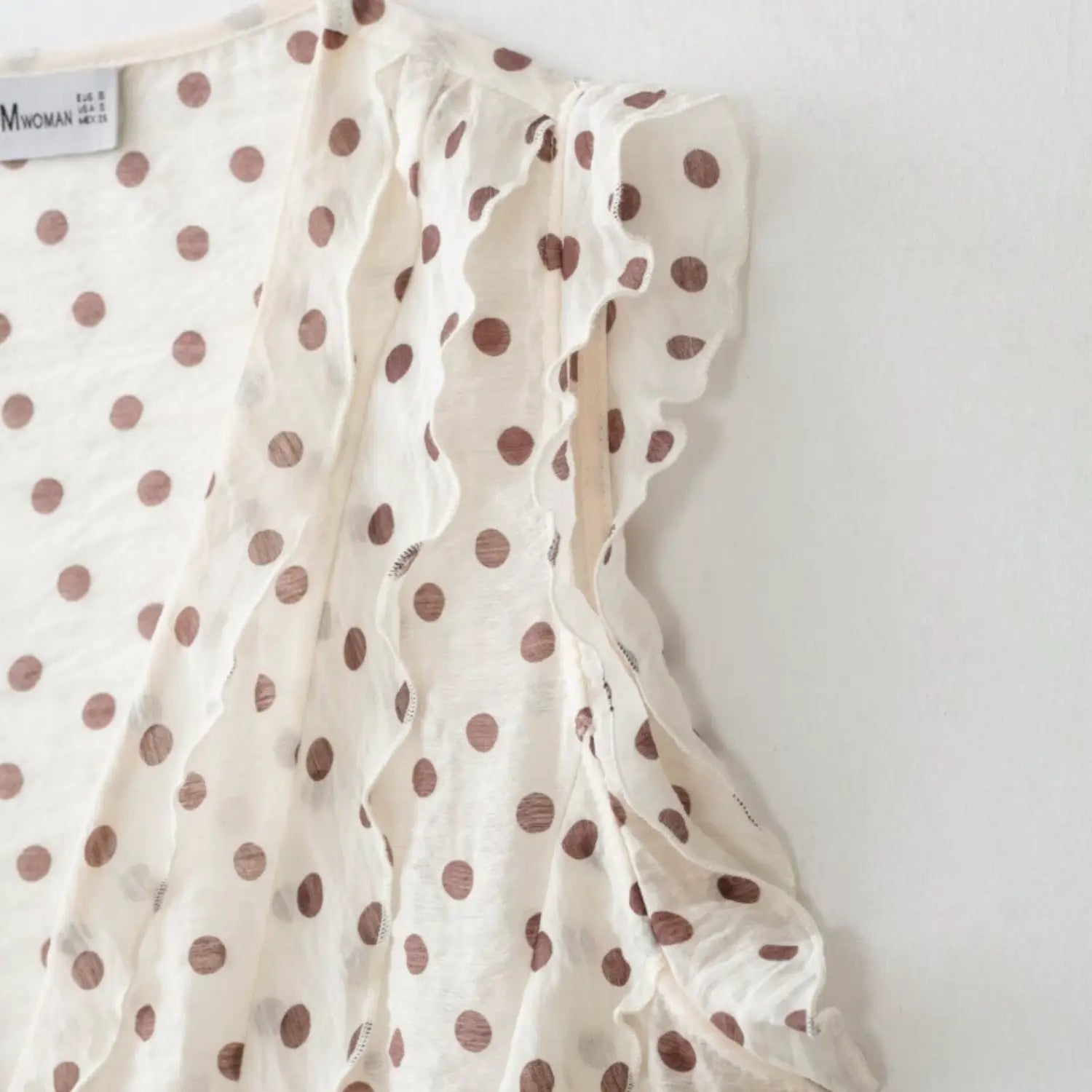 Side shoulder close-up of sleeveless armhole with integrated wavy frill trim, neat finished seams