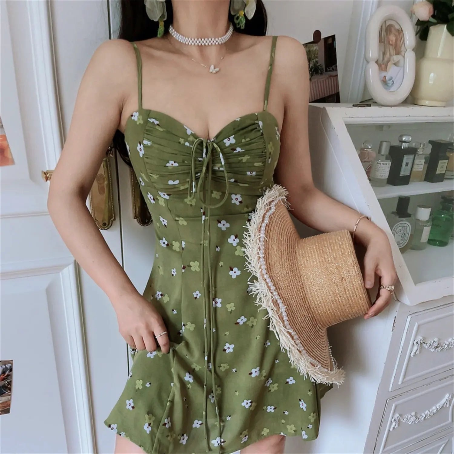 Avocado green tiny floral cami mini dress full front model shot, high waisted a-line mini skirt matched with brown ankle boots wood floor full body display