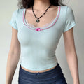 Front lifestyle shot on model of baby blue jacquard knit slim crop tee, U neck with inner lace, pink piping & small bow, everyday fitted short sleeve top
