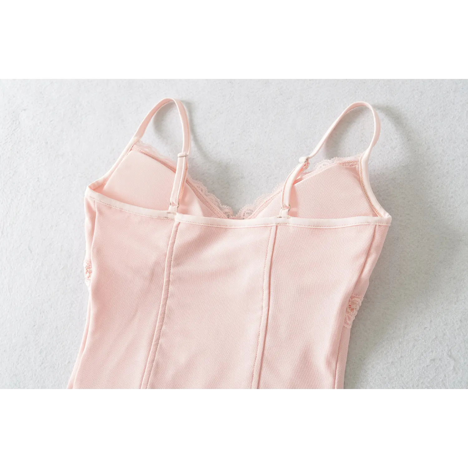 Whole back flat lay view, plain solid back panel, two adjustable straps with sliders, vertical rear shaping seams, back V hollow design