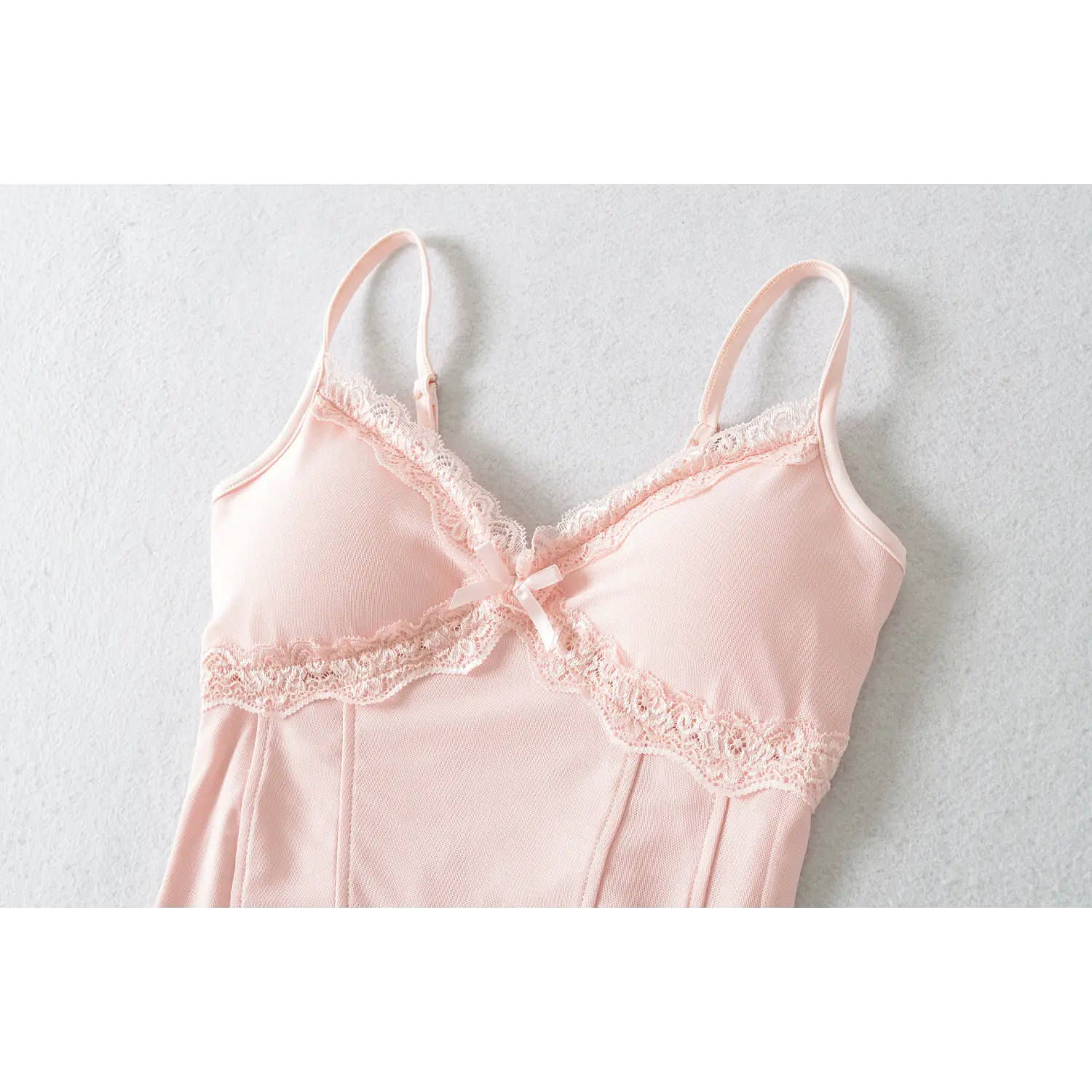 Full front flat lay view, baby pink mesh fabric, scalloped lace V-neckline, center front satin bow ornament, cross lace chest splicing, vertical corset shaping seams, adjustable thin shoulder straps