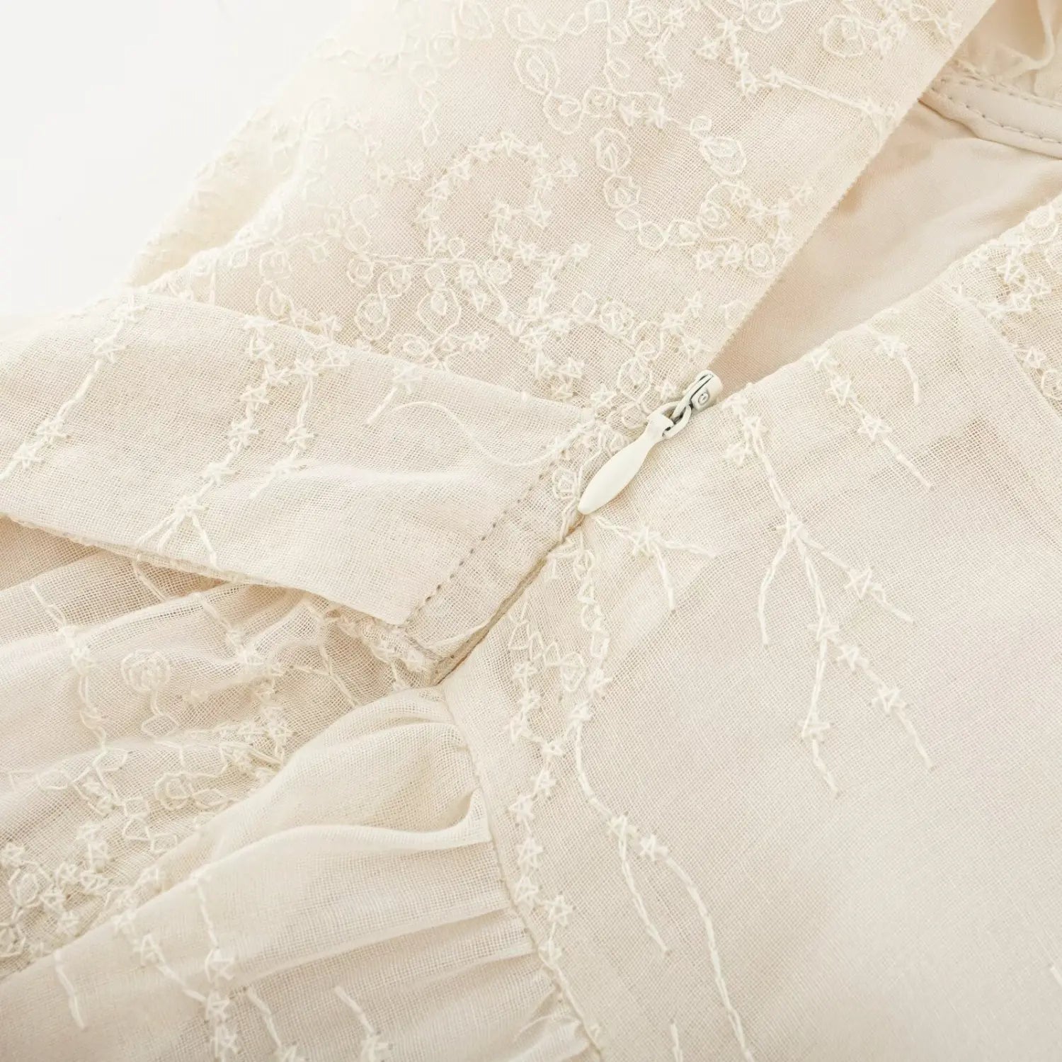 Back center white teardrop pull invisible zipper embroidered dress macro close-up, matching fabric binding smooth slide easy wear stitching detail shot