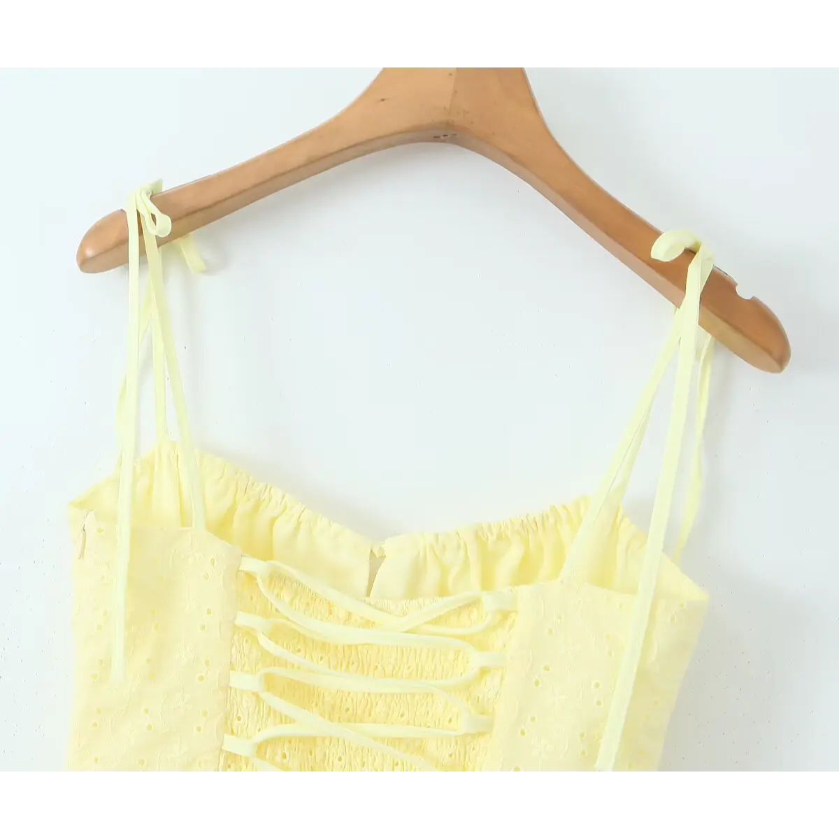 Back bodice close-up, full elastic smocked waist with cross lace-up ribbon detail on yellow embroidered dress.