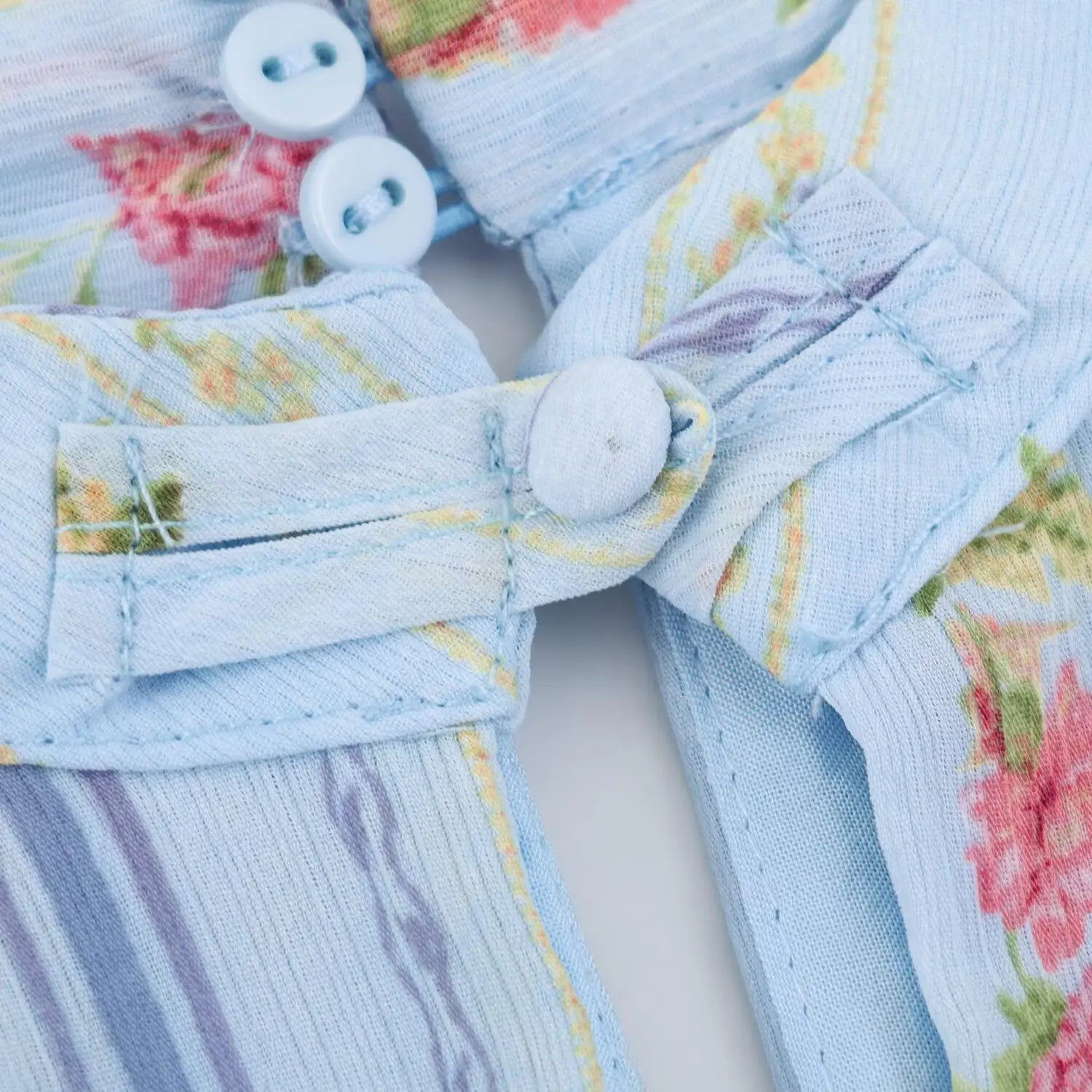 Back neck button placket macro shot, three matching light blue round plastic buttons with fabric loop fastener