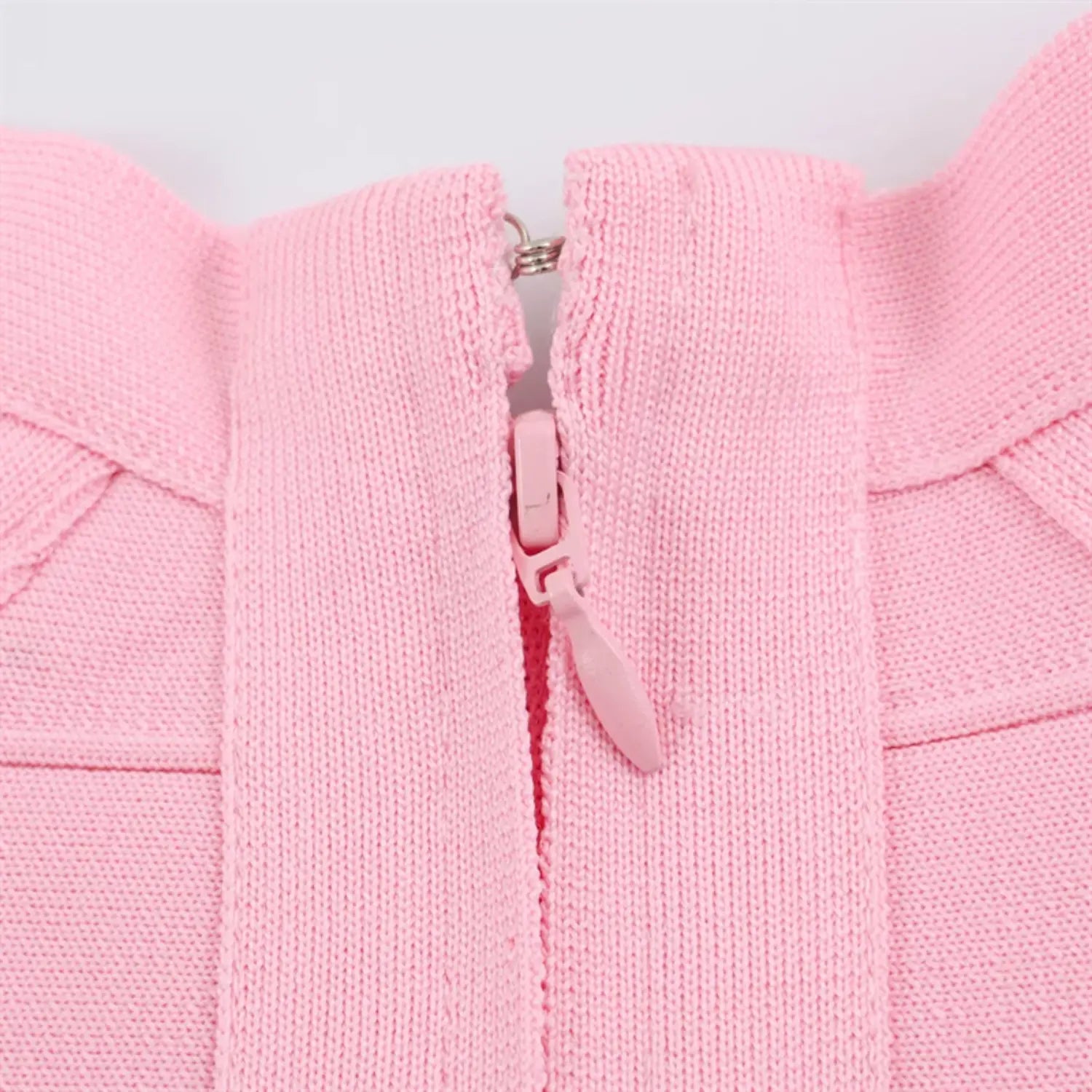 Center back zipper close-up, matching blush pink plastic pull tab, fine invisible tooth zipper, ribbed bandage knit surrounding fabric