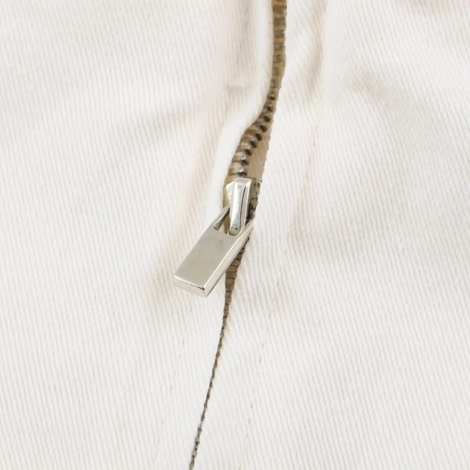Close up of silver metal vertical back zipper with flat pull tab on white mini dress