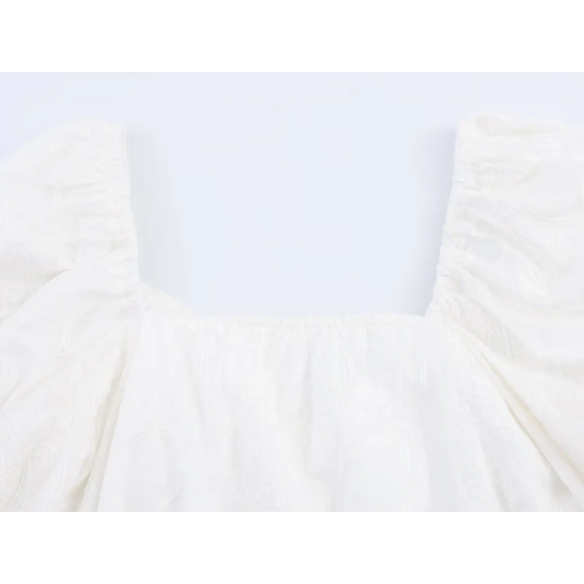 Back view close-up of square elastic neckline on white puff sleeve embroidered crop top