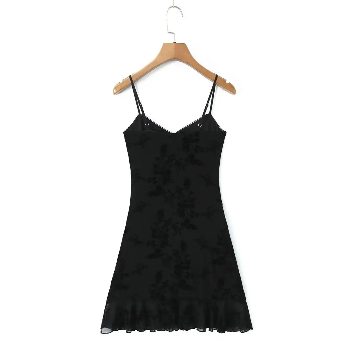 Full back view of a black flocked floral slip dress on a wooden hanger, showcasing the double spaghetti straps and sheer ruffled hem.
