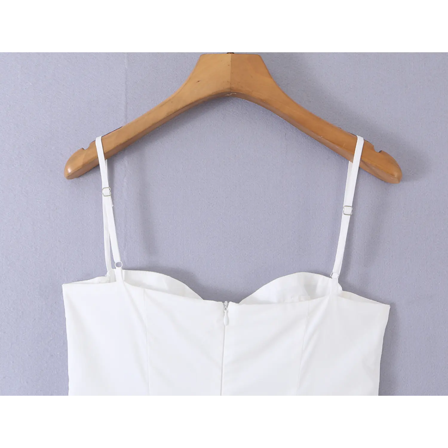 Close-up adjustable spaghetti straps and invisible back zipper of white fitted mini dress