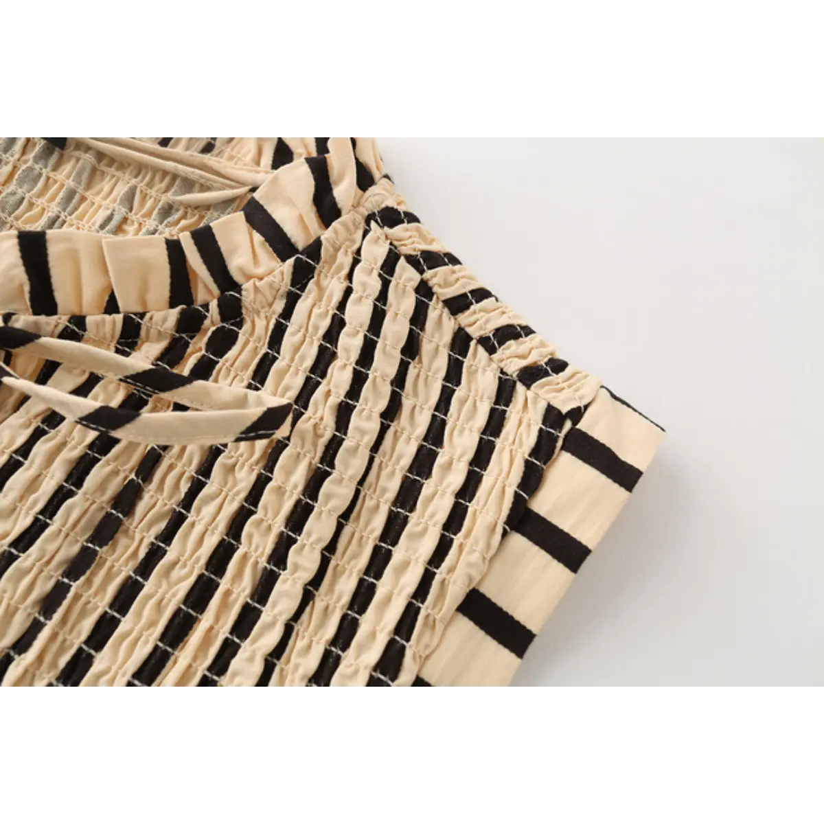 Close-up of the top's cap sleeve, ruffled neckline, and tie detail.