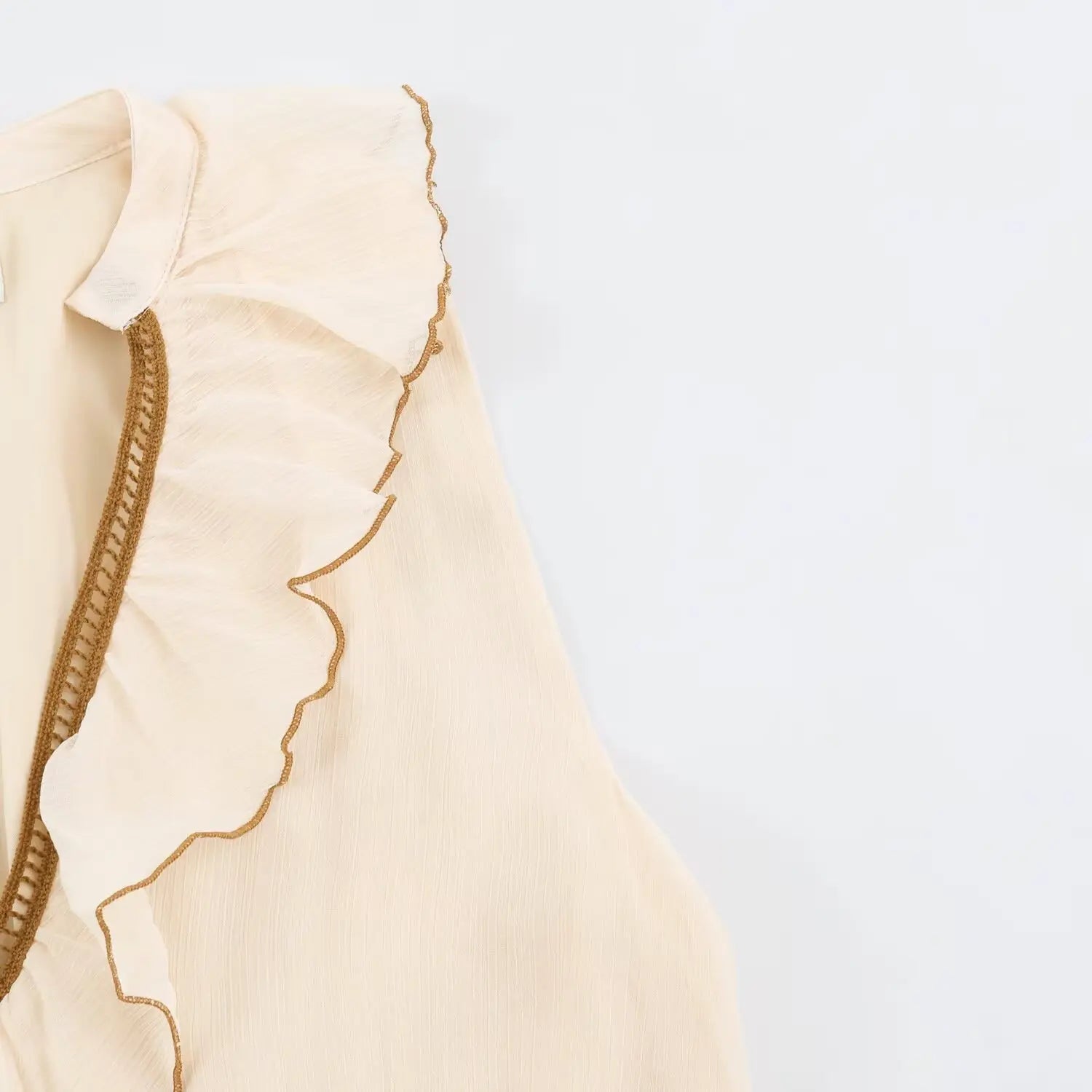 Side detail of shoulder flounce ruffle with brown edge trim beige tiered dress