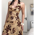 Woman wearing a beige halter mini dress with a brown floral print, posed to highlight the cowl neckline and fitted bodice.