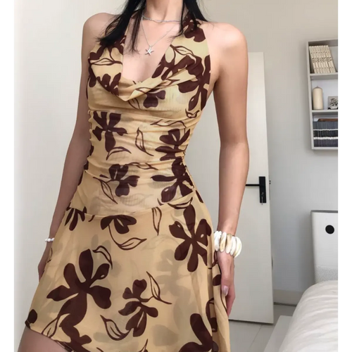 Woman wearing a beige halter mini dress with a brown floral print, posed to highlight the cowl neckline and fitted bodice.