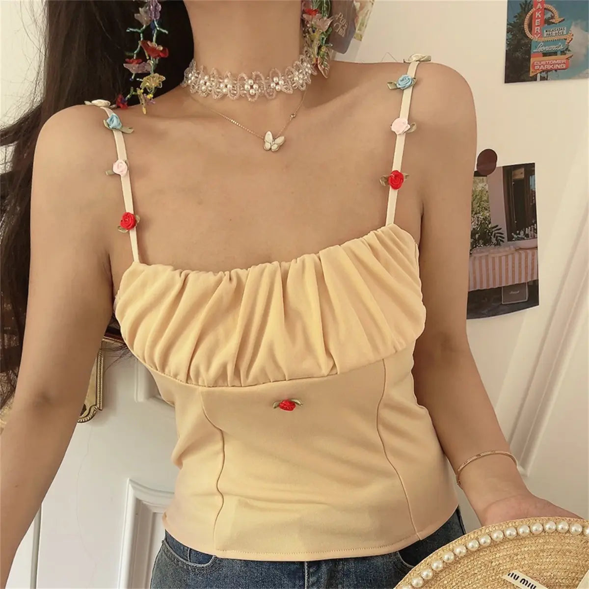 The beige floral-strap cami top styled with a pearl-trimmed straw hat.