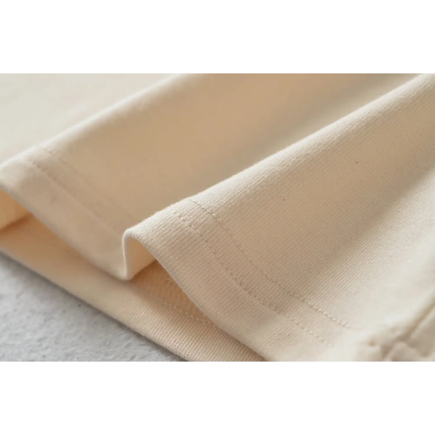 Fabric texture closeup of beige criss cross strap camisole, ribbed knit material