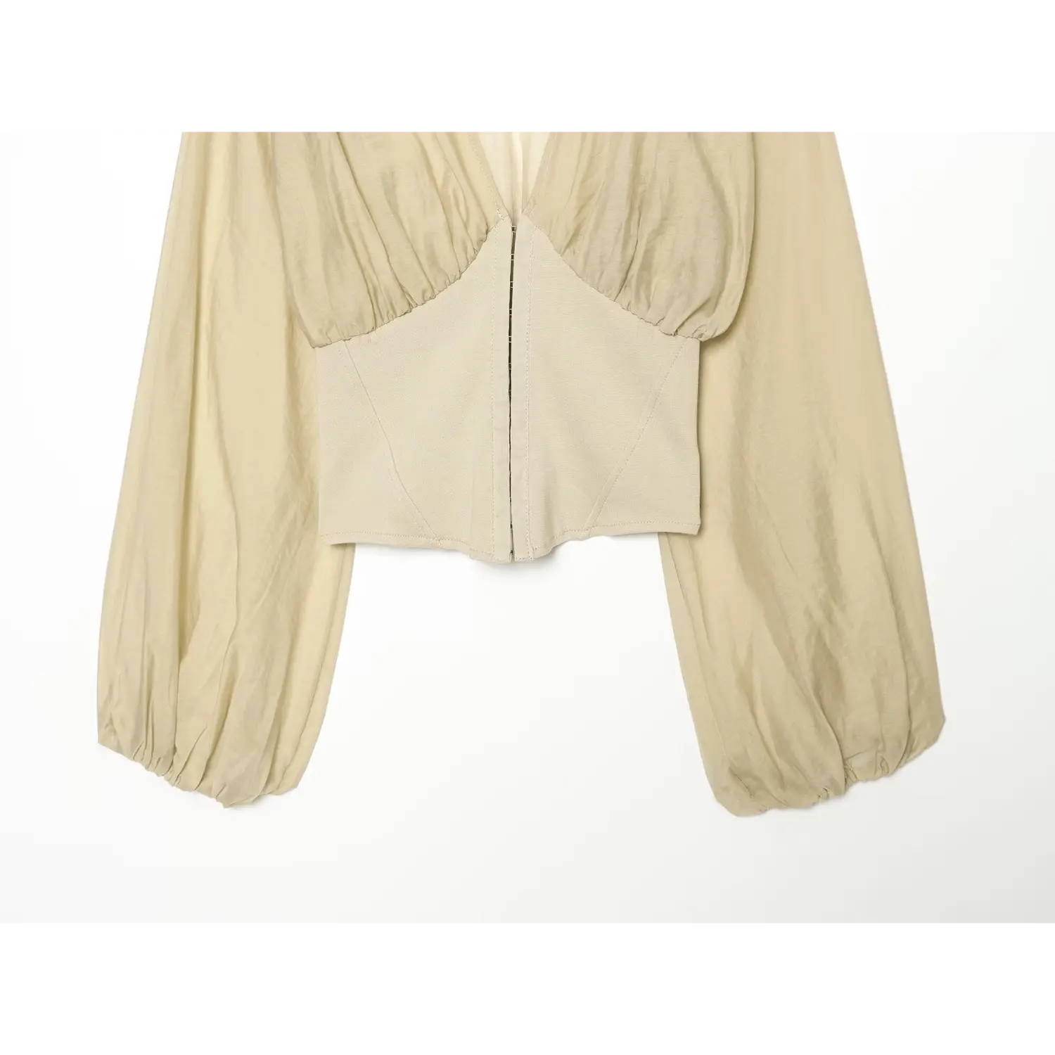 Partial shot showing structured corset waist and balloon long sleeves of beige crop top