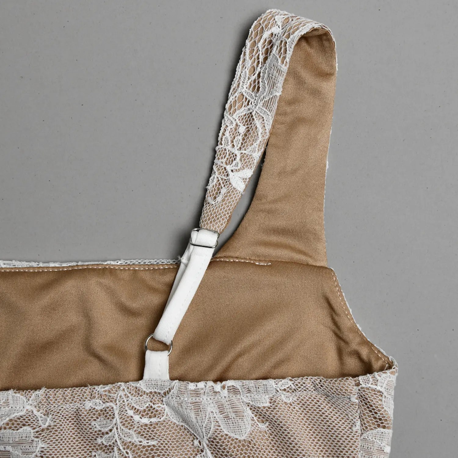 Extreme close‑up adjustable metal buckle on lace covered cami strap with beige inner lining