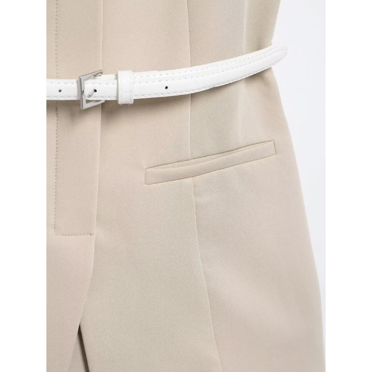 Close-up of white textured leather belt beside fabric fake pocket, fine twill suiting texture, precise pocket edge topstitch