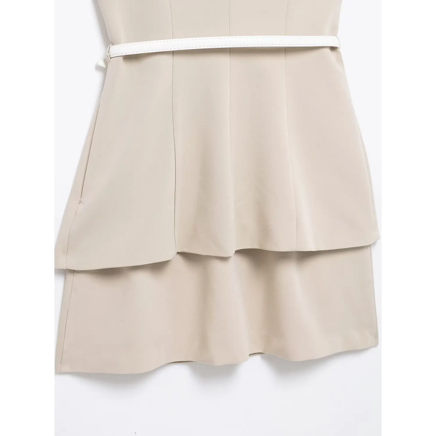 Mid-body flat close-up, vertical tailored darts shaping waist, overlapping blazer hem creating tiered silhouette, thin white belt cinching natural waist