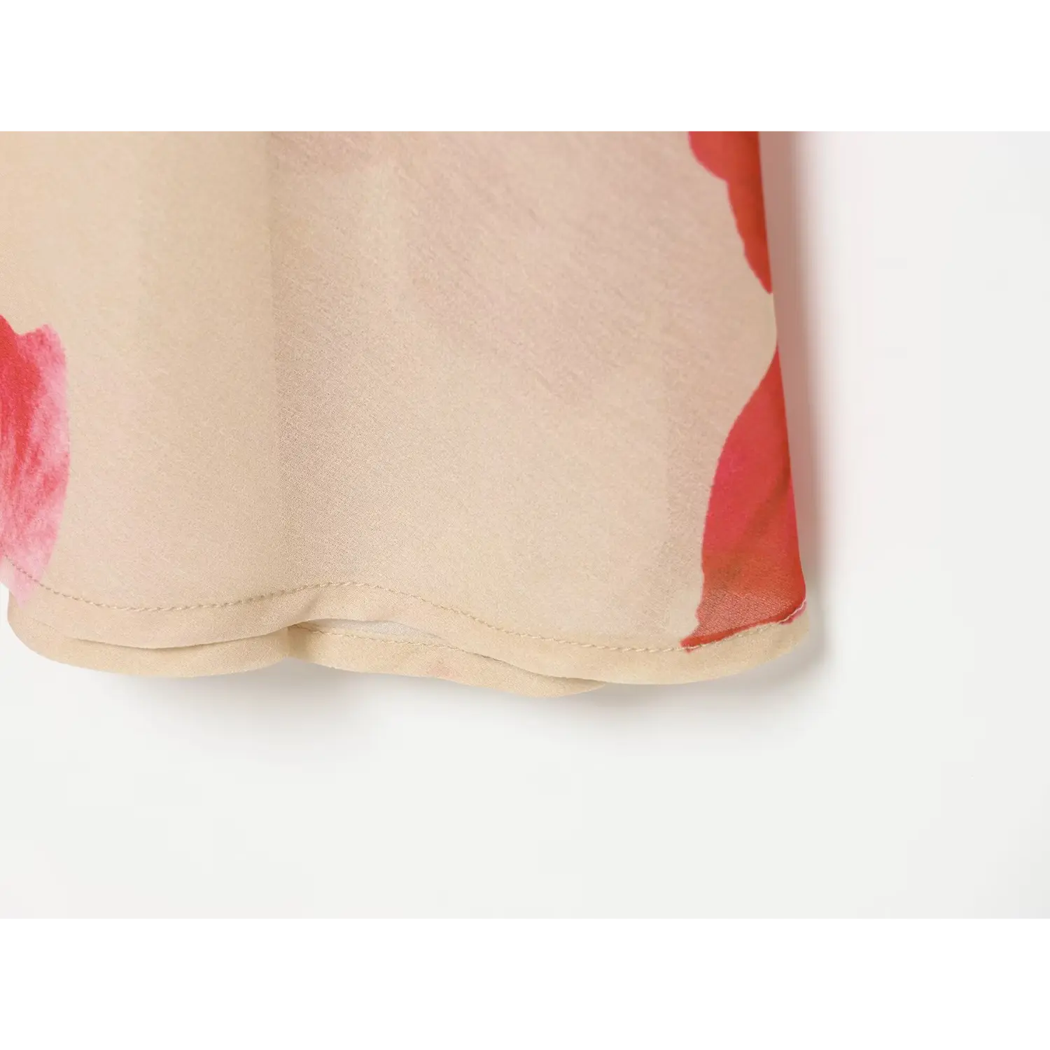 Close-up of beige floral maxi dress hem, double layer finish, red pink flower print, neat stitching