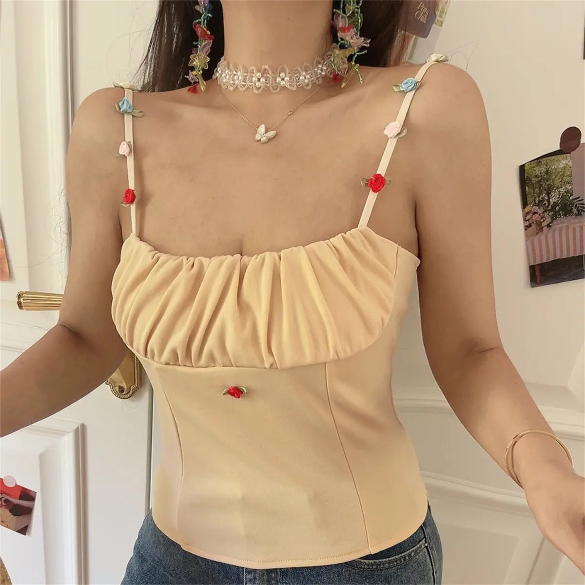 Close-up of the beige cami top, highlighting the multicolored floral appliqués on the straps.