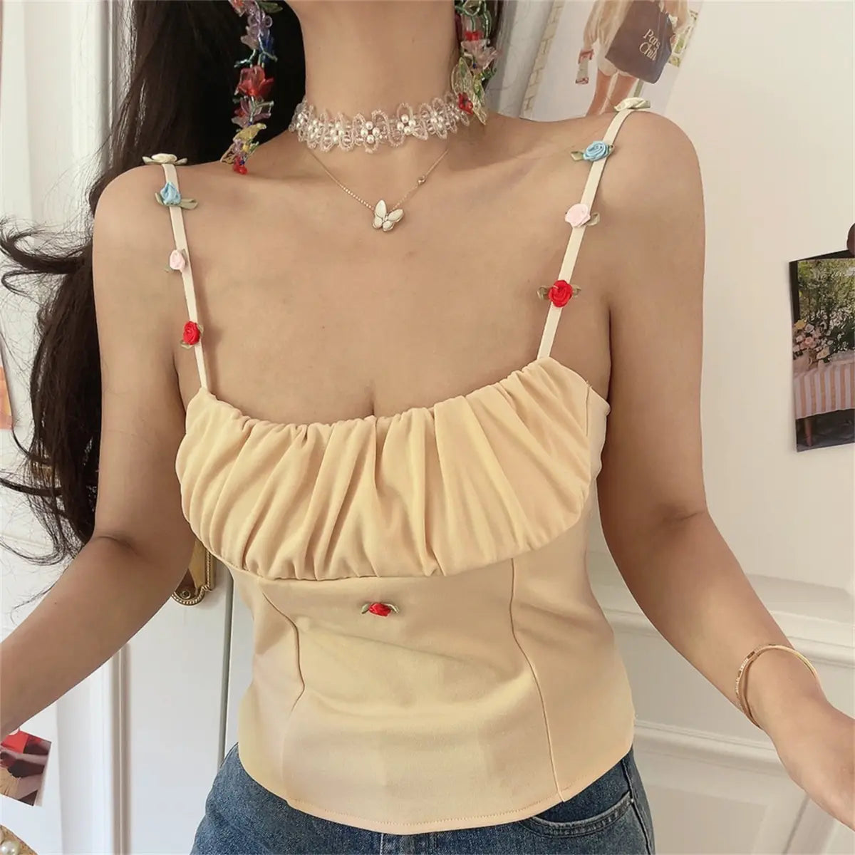 Front view of the beige cami top with floral appliqué straps and ruched bust.
