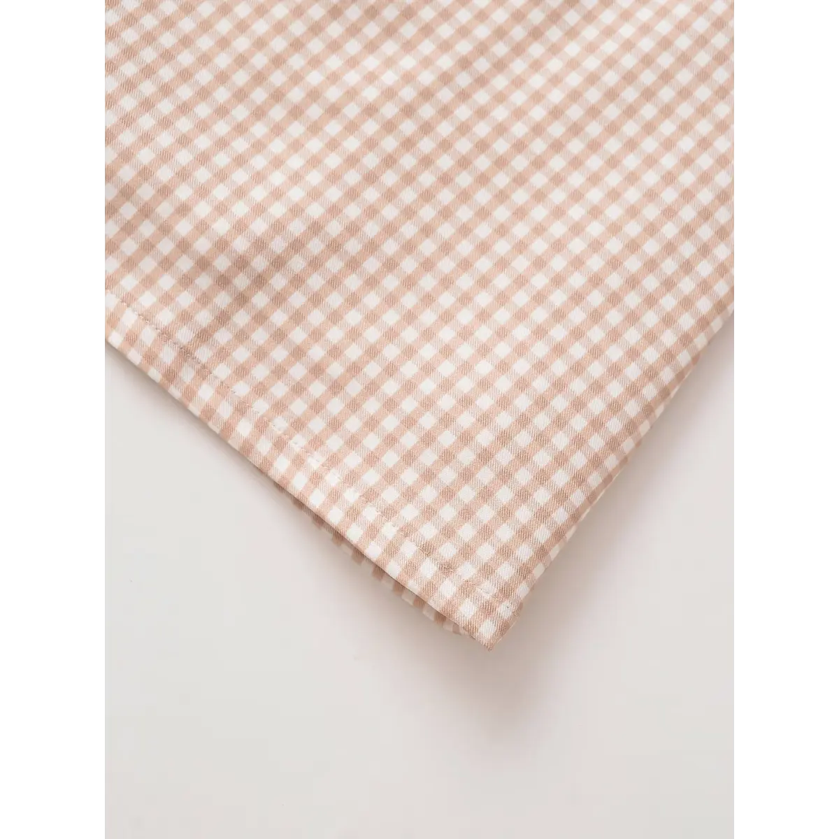  Close-up view of the side seam on a beige gingham mini dress, showing the stitching and pattern alignment.