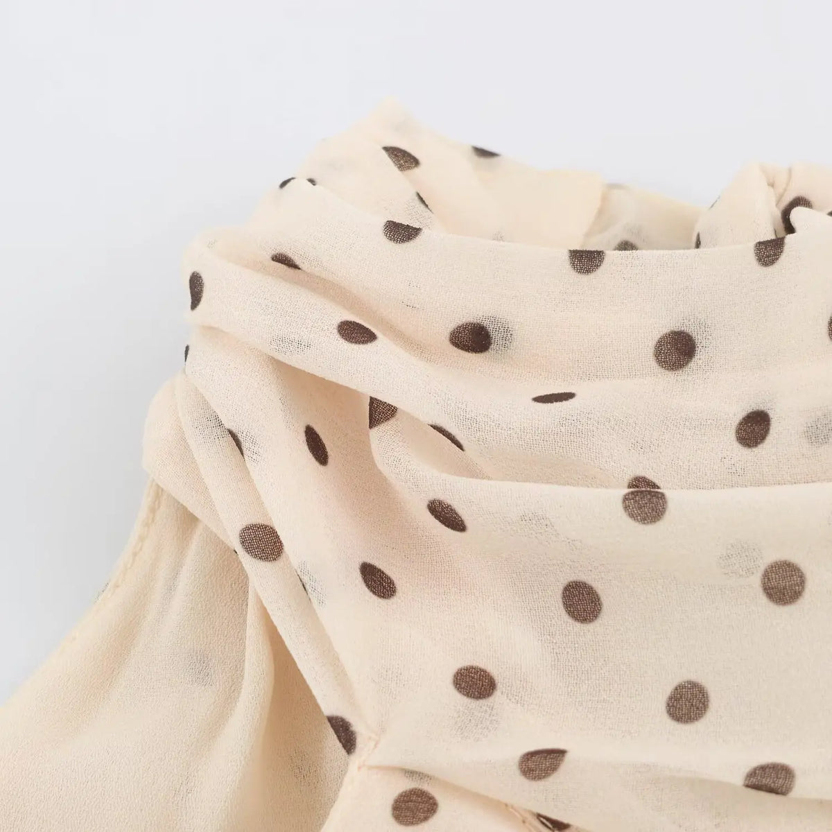 Close‑up of smocked elastic waistband on beige polka dot maxi dress