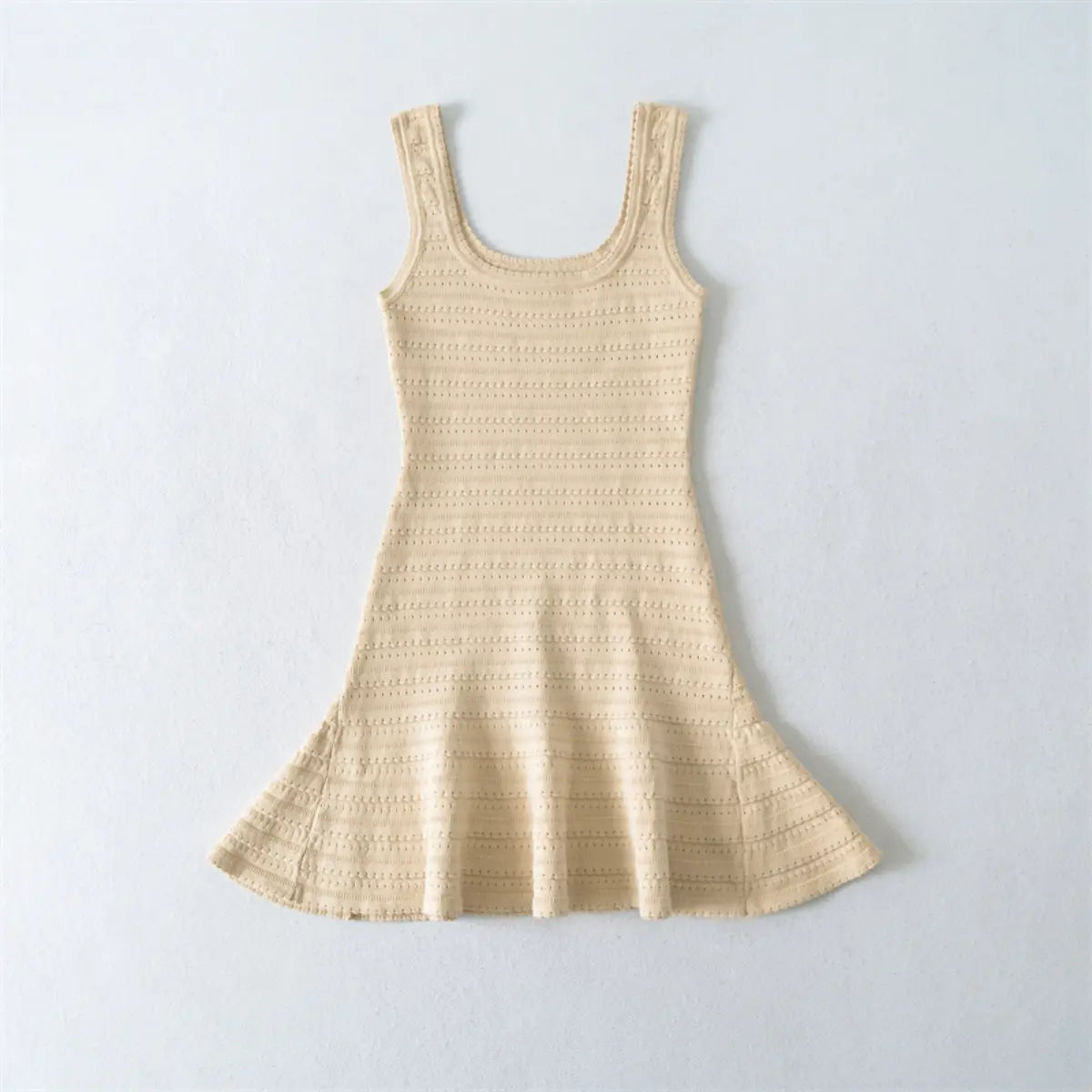 Flat lay view of a beige knit mini dress, showing the full silhouette with square neckline, fitted bodice, and flared skirt.