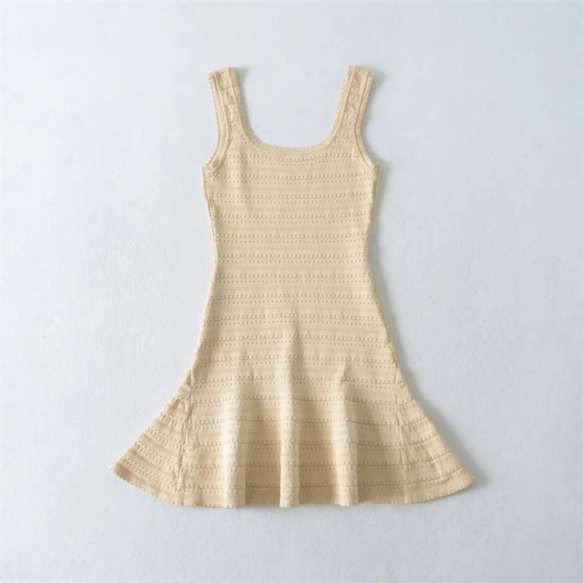 Flat lay view of a beige knit mini dress, showing the full silhouette with square neckline, fitted bodice, and flared skirt.