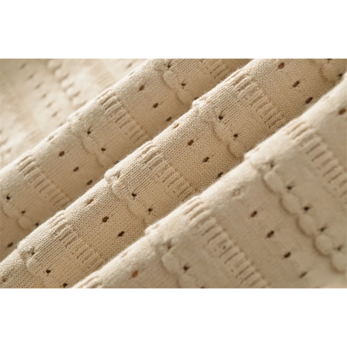 Close-up detail of the openwork knit fabric on a beige mini dress, showing the horizontal stripes and eyelet texture.