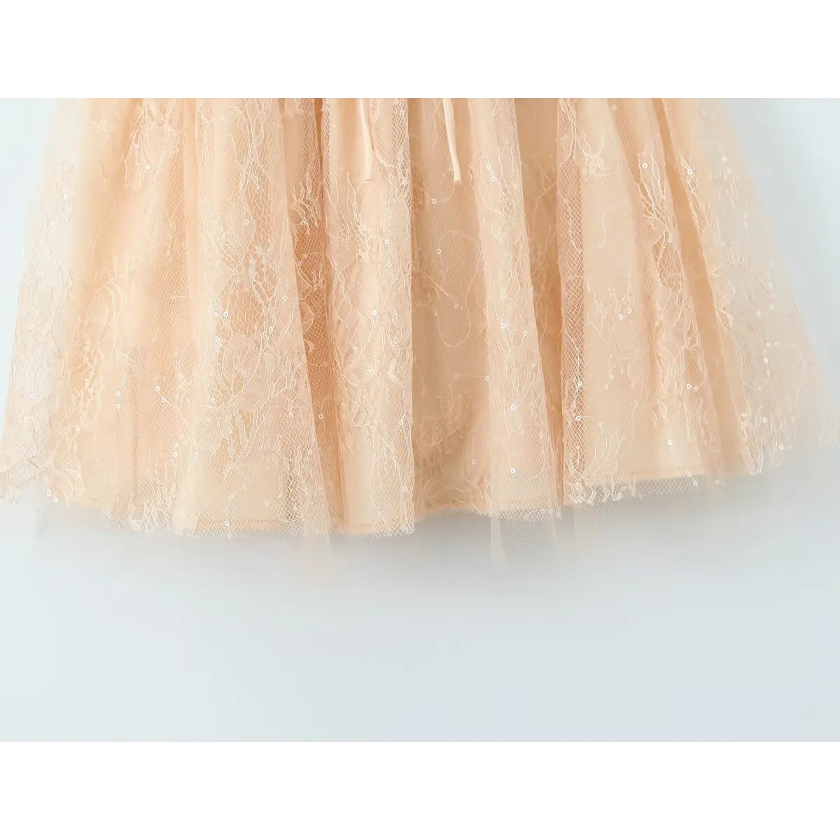 Close-up of the lace and tulle fabric texture on the beige dress skirt