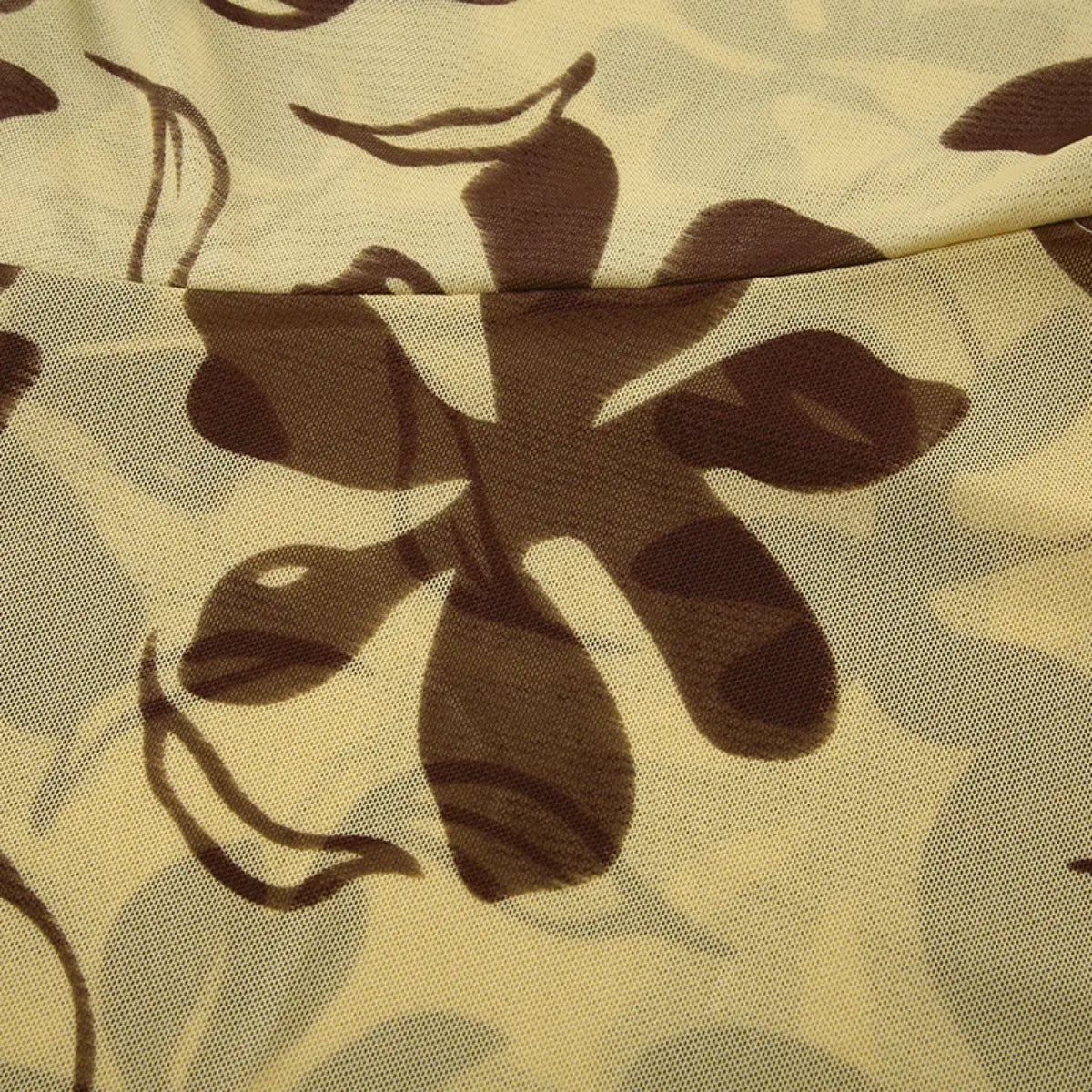 Macro view of beige mesh fabric with a brown floral print, highlighting the print's opacity against the sheer background.