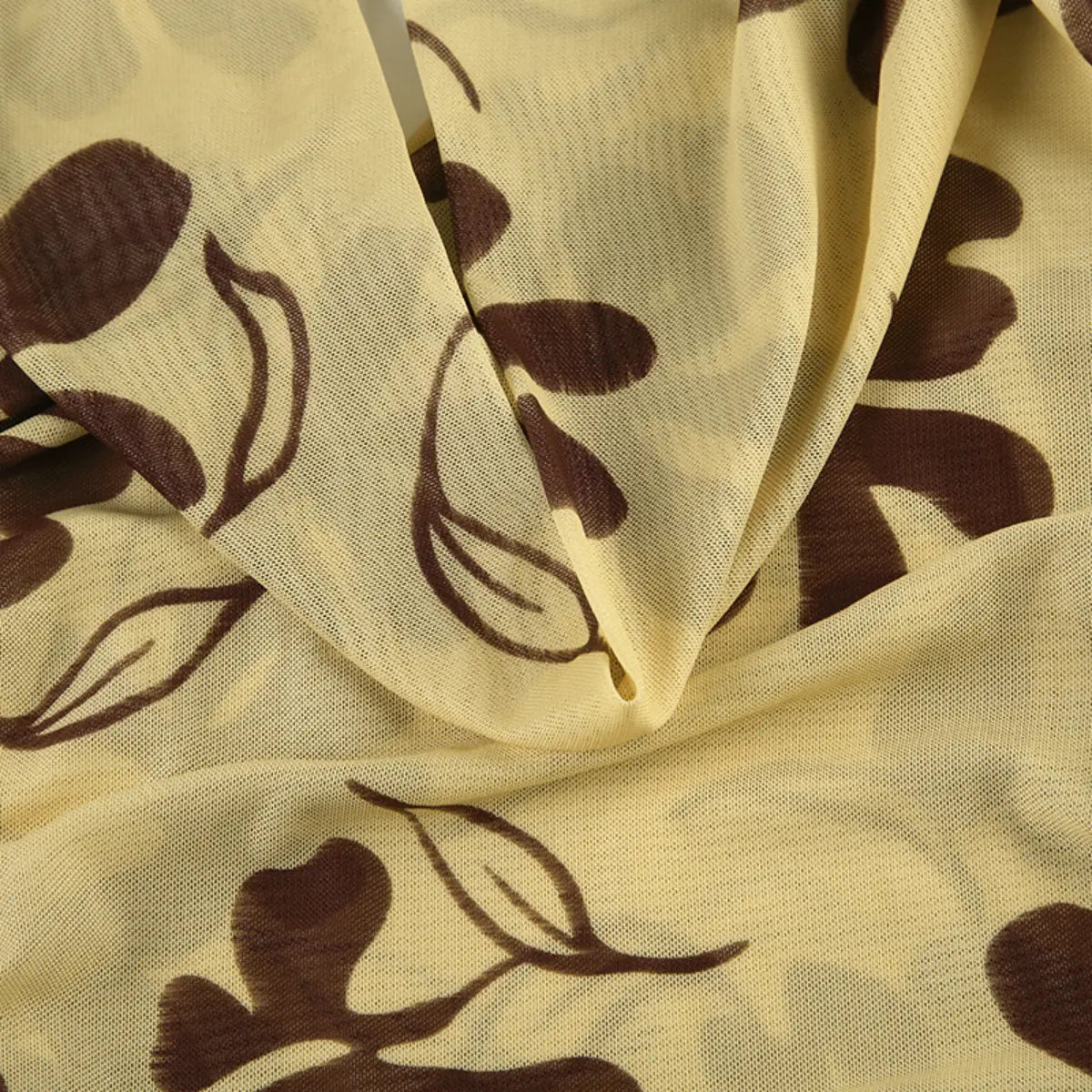 Close-up shot of beige mesh fabric with a brown floral print, showing the sheer texture and detailed flower pattern.