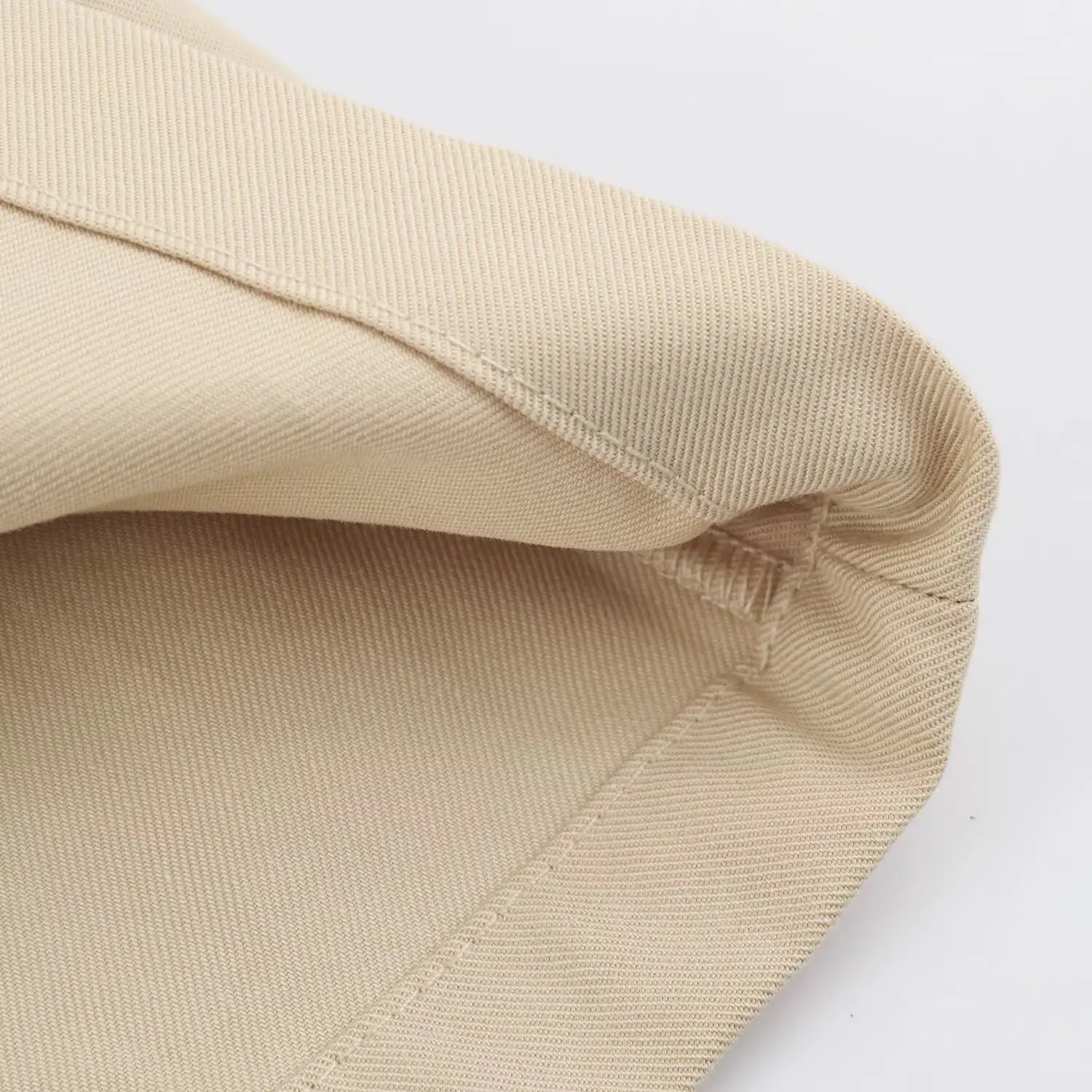 Macro close-up of finished hem stitching on beige fabric mini skirt