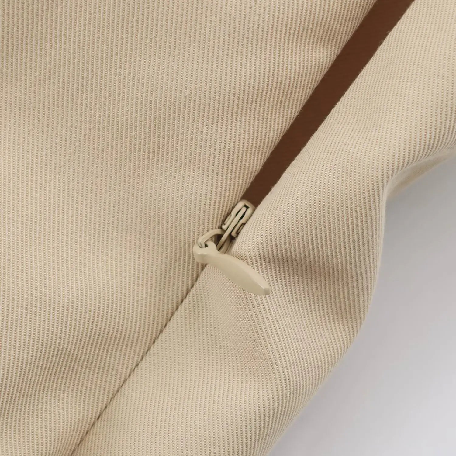 Close-up of matching invisible side zipper on beige woven mini dress
