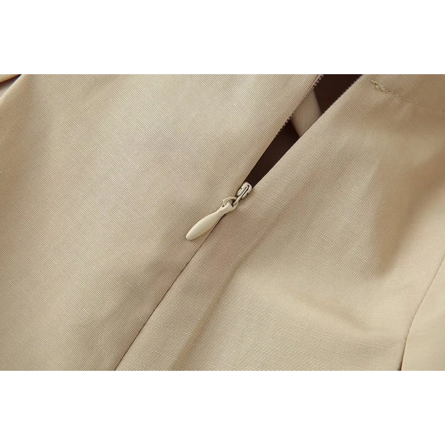 Close‑up workmanship of side invisible zipper on beige belted mini dress