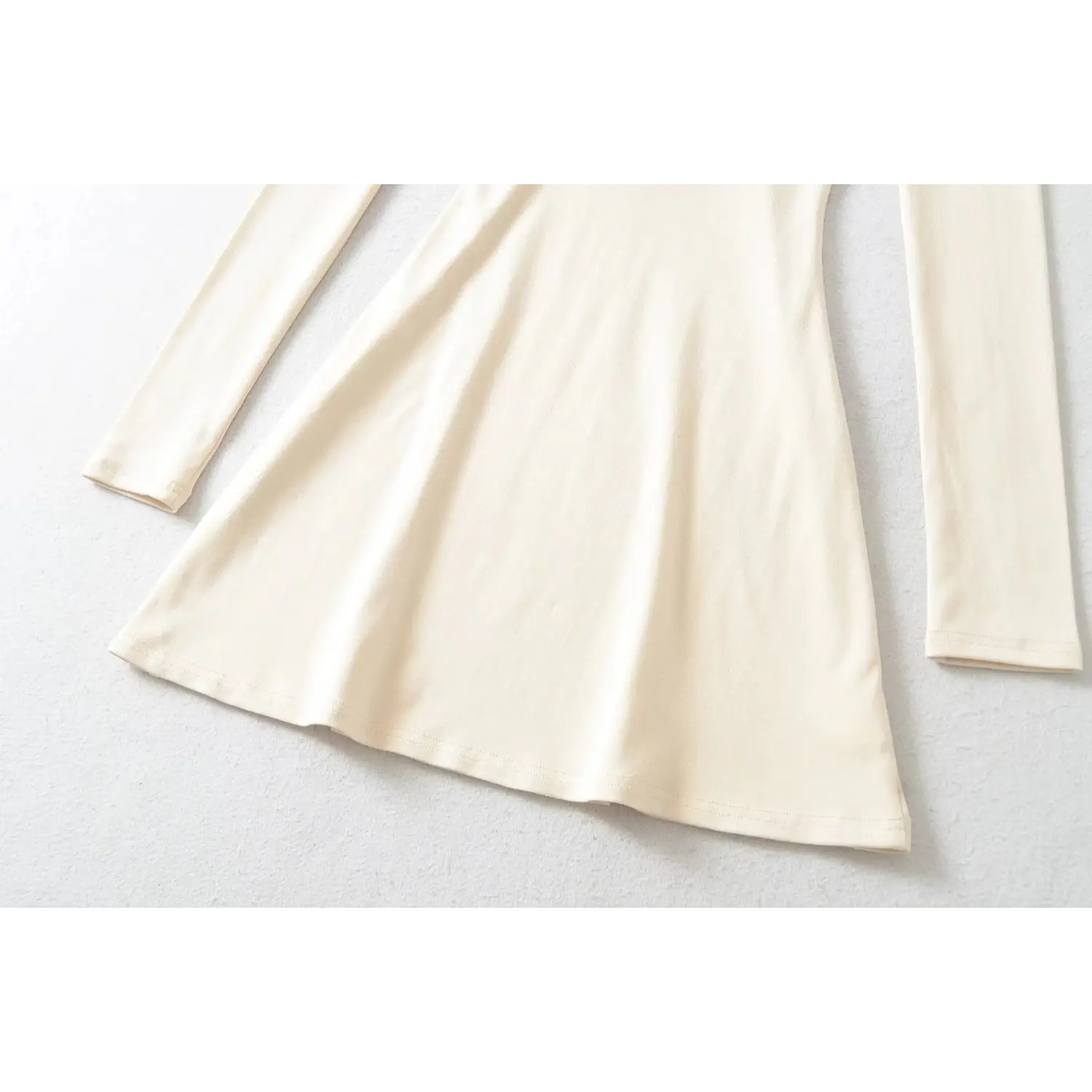 Close up of beige mini dress flared skirt hem, soft stretch knit fabric, gentle flowy silhouette